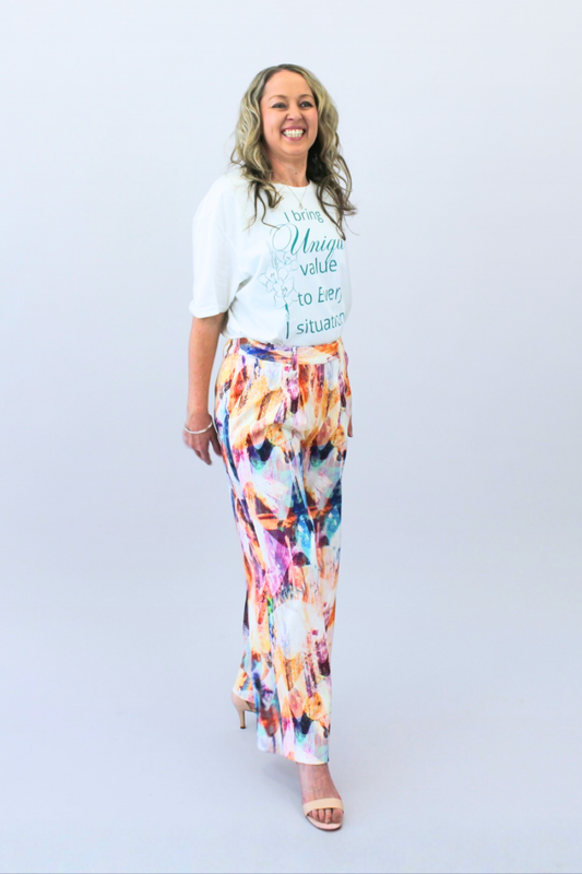 Woman wearing a white t-shirt with text and colorful pants on a light gray background