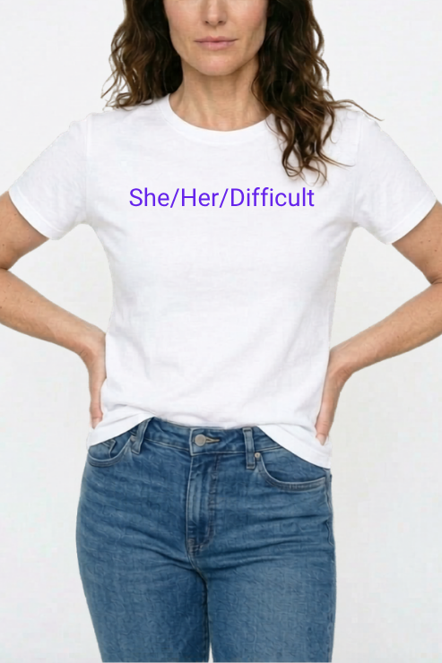 Person wearing a white t-shirt with 'She/Her/Difficult' text on a plain background