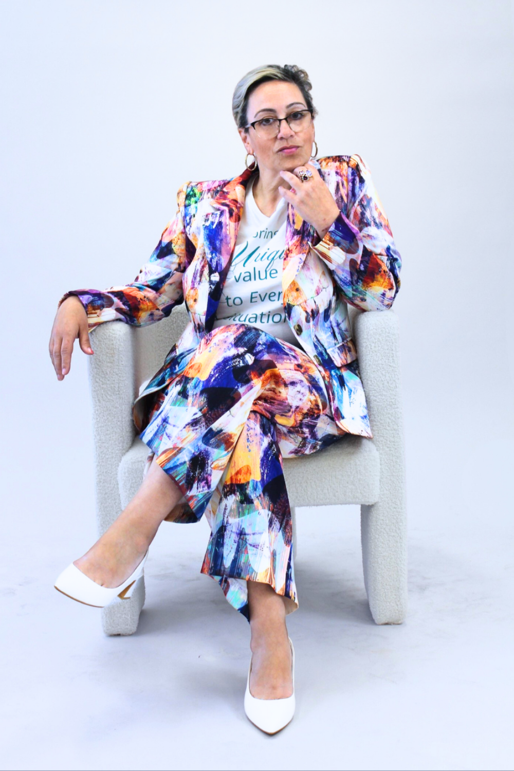 Woman sitting on a chair wearing a colorful outfit with a white background