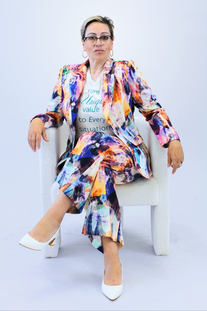 Woman sitting on a white chair wearing a colorful outfit with a white background