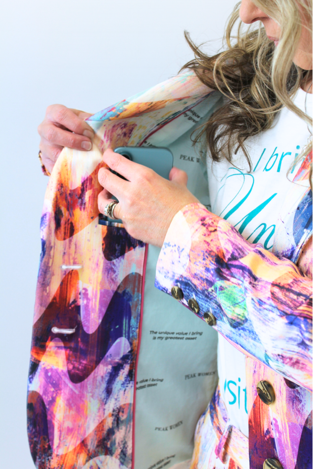 Person holding a phone with a colorful jacket over their shoulders