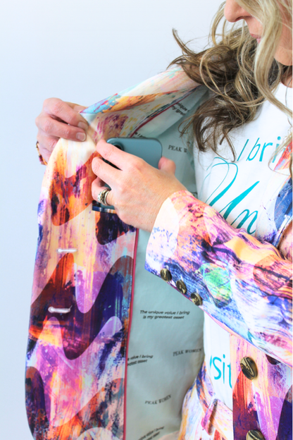 Person holding a phone with a colorful jacket over their shoulders