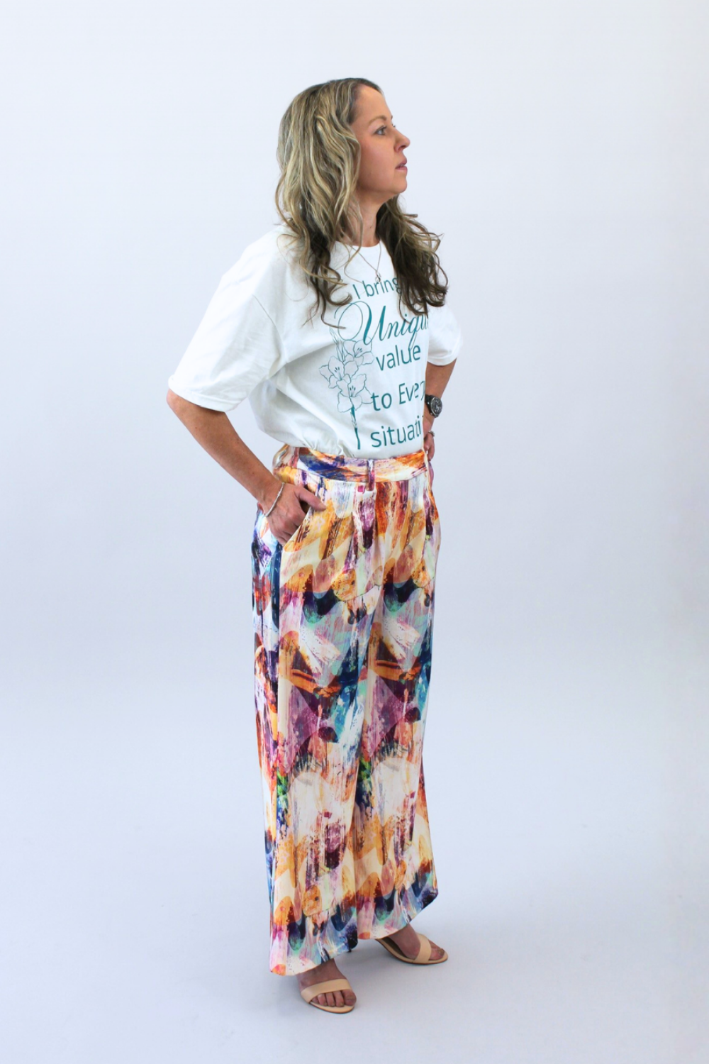 Woman wearing a white t-shirt with text and colorful pants on a white background