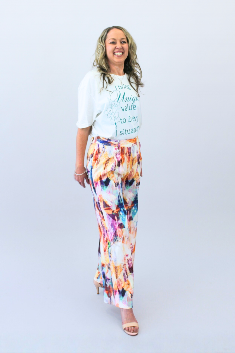 Woman wearing a white t-shirt with text and colorful pants on a light gray background