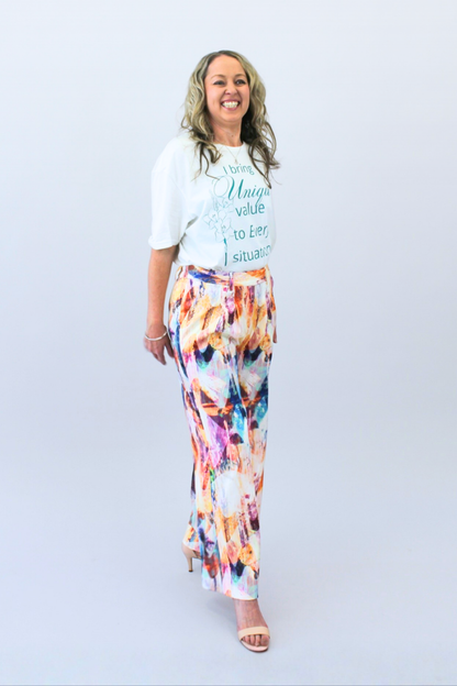 Woman wearing a white t-shirt with text and colorful pants on a light gray background