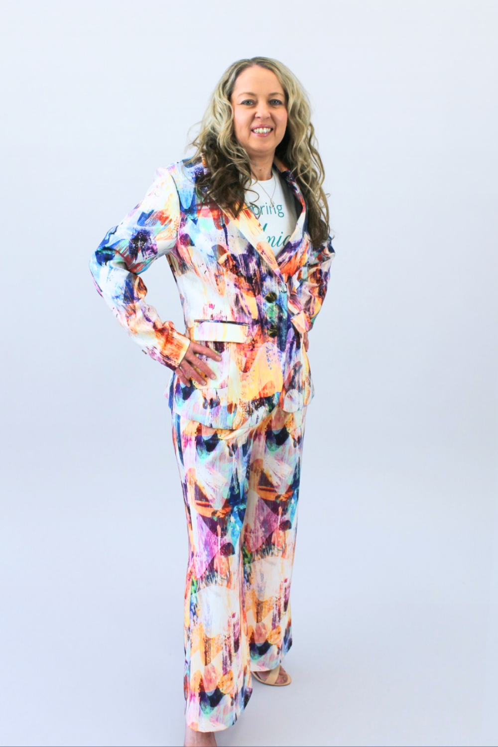 Woman wearing a colorful outfit with a white background hands on hips