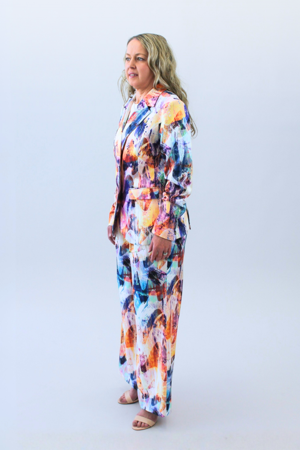 Woman wearing a colorful print outfit on a white background posing on the side