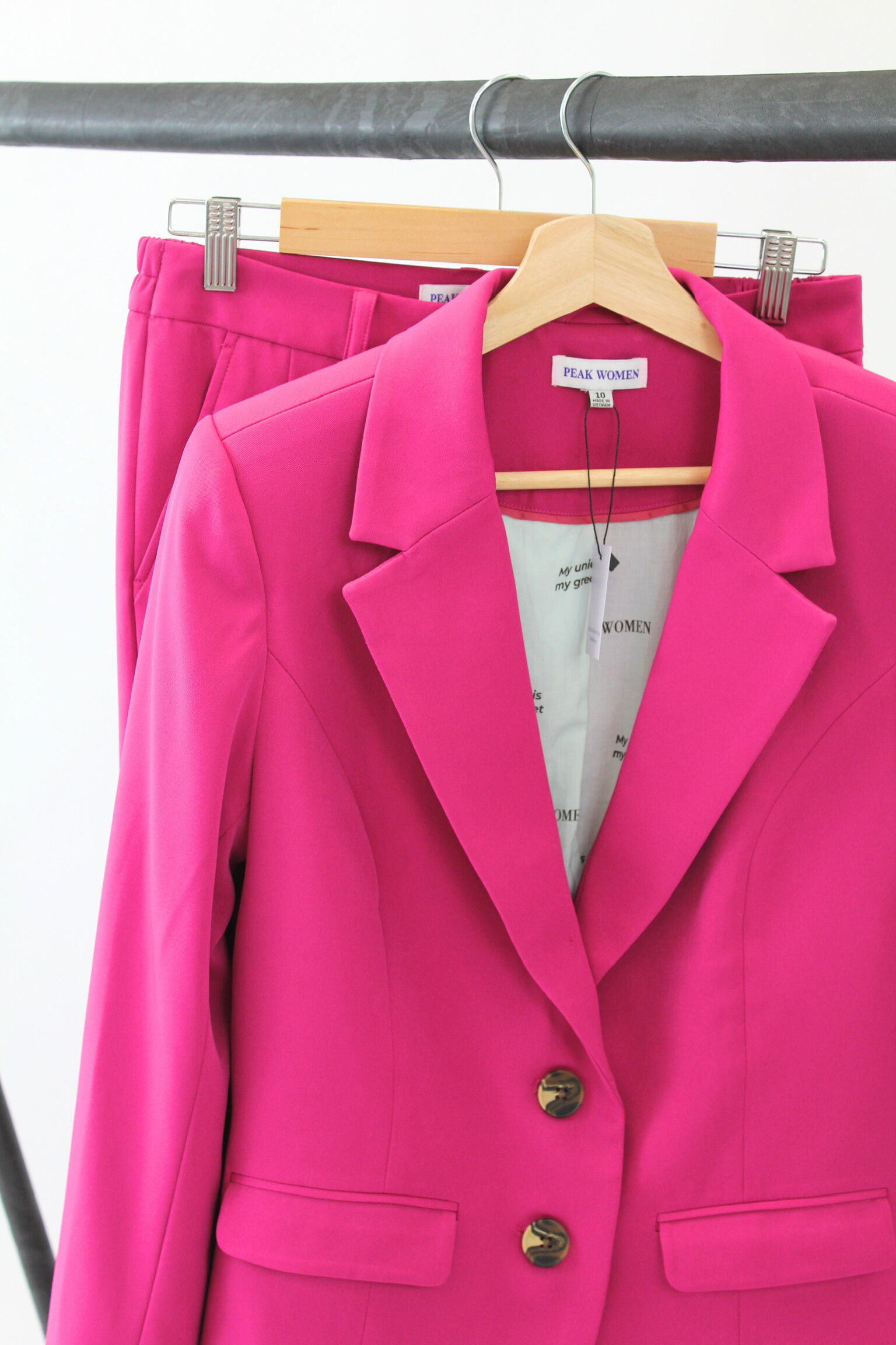 Pink blazer on a hanger against a white background
