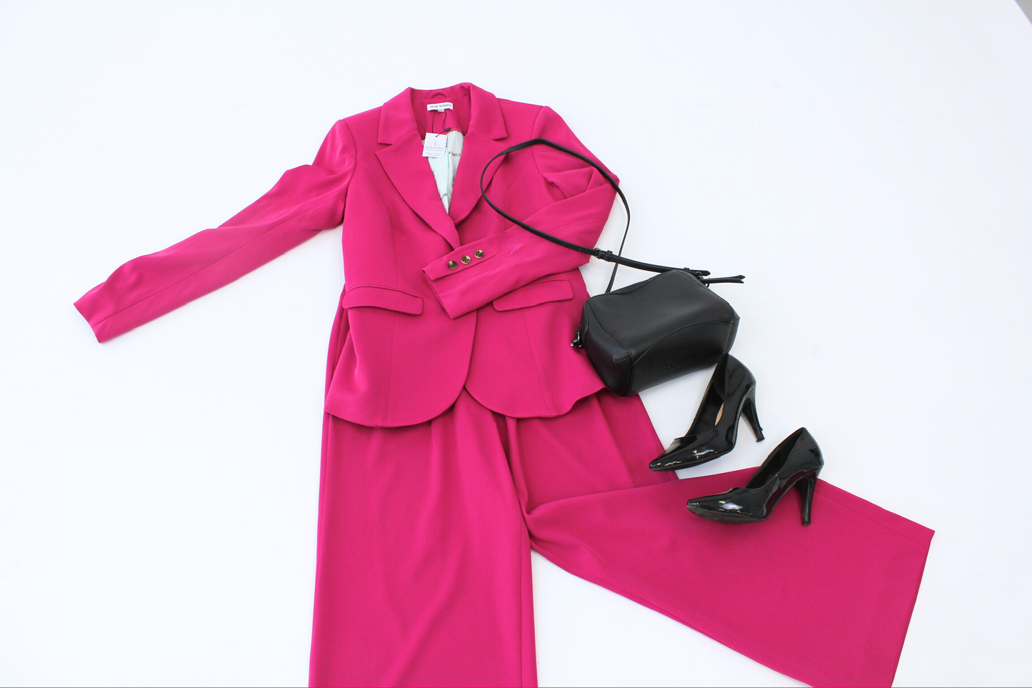 Pink suit with black handbag and high heels on a white background
