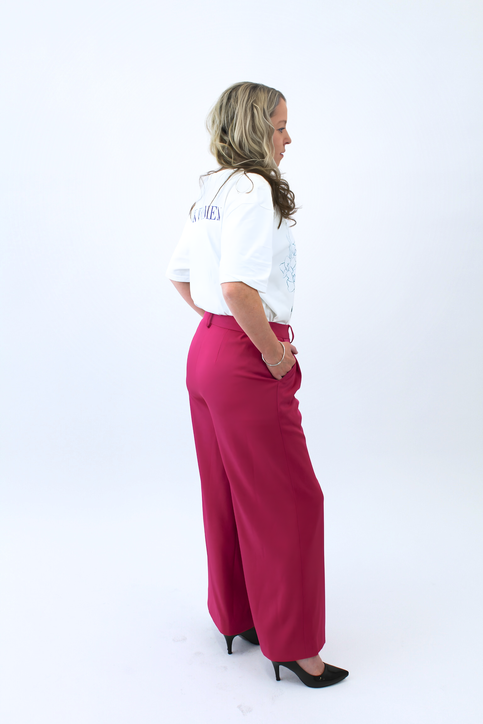 Woman wearing a white shirt and pink pants on a white background