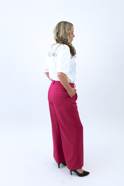 Woman wearing a white shirt and pink pants on a white background