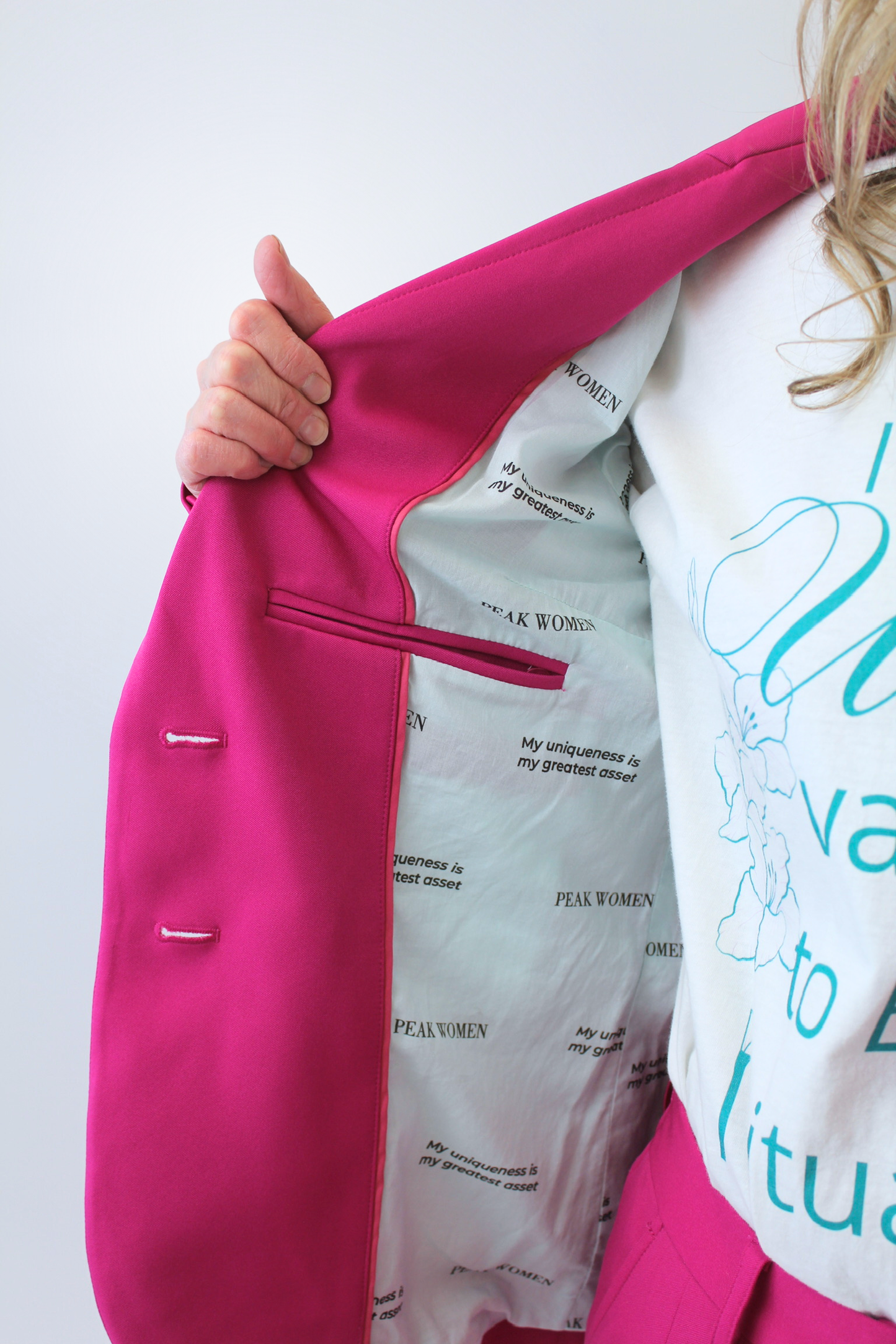 Person wearing a bright pink jacket over a white shirt with text, on a light gray background