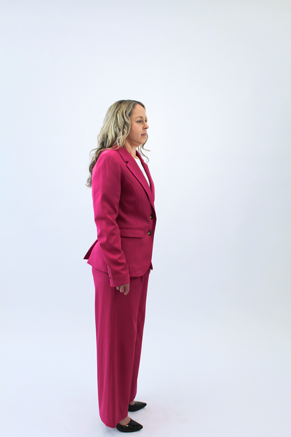 Woman wearing a pink suit standing against a white background