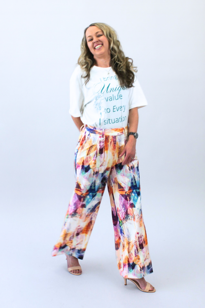 Woman wearing a white t-shirt with text and colorful pants on a white background