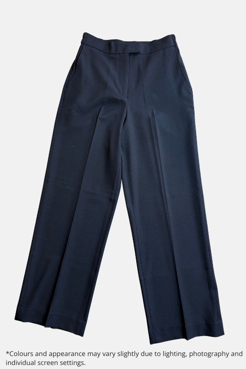 A pair of black tailored trousers laid flat on a speckled light gray floor. The trousers feature a straight, slightly relaxed leg, a clean waistband, and front creases.