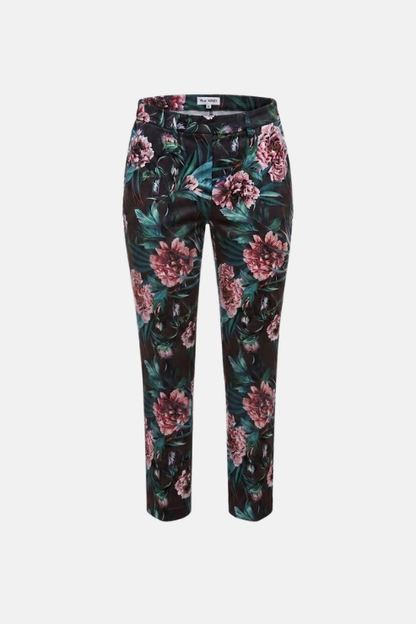 A pair of slim-fit trousers featuring a dark green and black tropical floral print with pink peony flowers, shown against a plain light gray background.