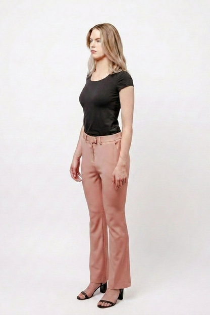 A woman modeling a black short-sleeve top and dusty rose flare pants with black heeled sandals, standing against a plain white studio background.