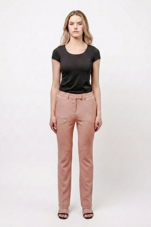 A woman stands against a plain light background wearing a black short-sleeve crewneck t-shirt and dusty rose straight-leg trousers, paired with black sandals.