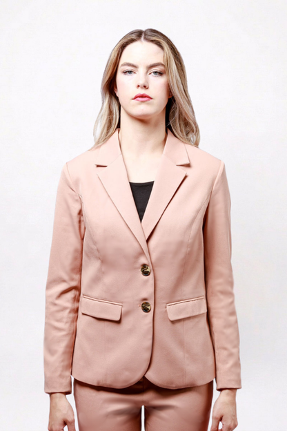 A woman modeling a dusty pink tailored blazer with two gold-tone buttons, paired with matching trousers and a black top, against a plain white studio background.