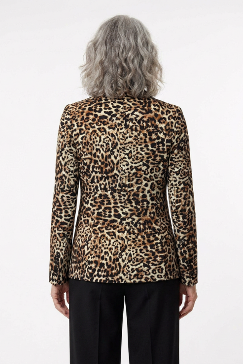 A person viewed from the back wearing a leopard-print blazer with black trousers, against a plain light gray studio background.