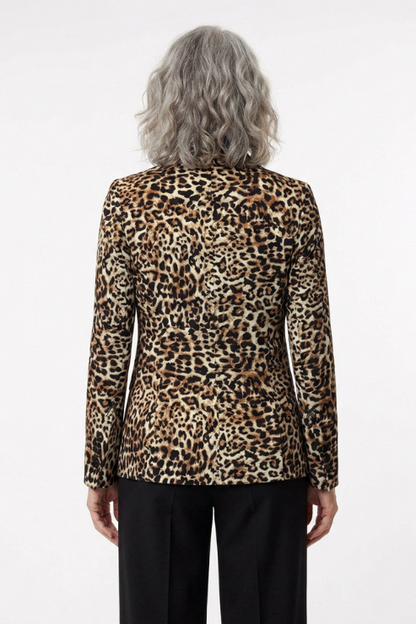A person viewed from the back wearing a leopard-print blazer with black trousers, against a plain light gray studio background.