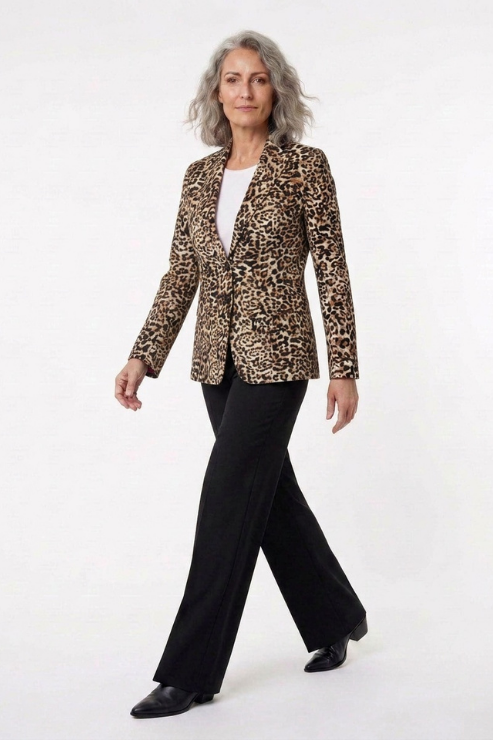A woman modeling a leopard-print blazer with black straight-leg trousers and black shoes, walking against a plain white studio background.
