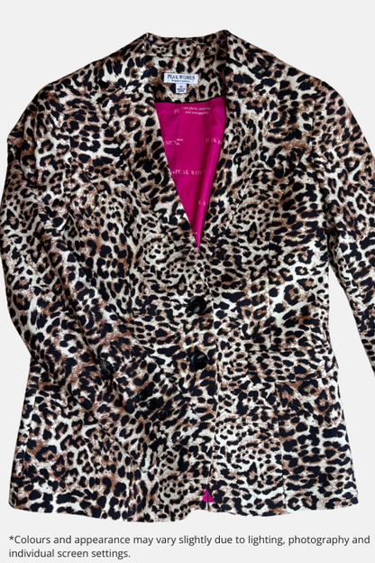 A leopard print blazer with a vibrant pink lining, laid flat on a speckled beige countertop.