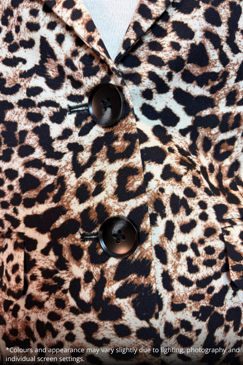 Close-up of a leopard print fabric with black buttons, showing the pattern and texture in detail.