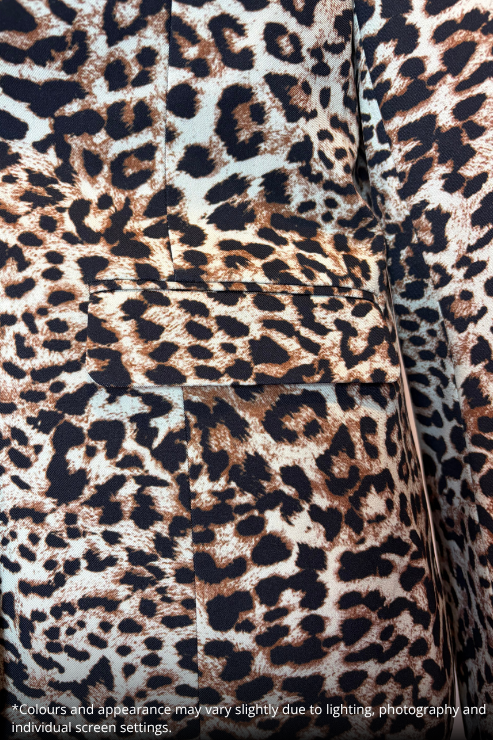 Close-up of leopard print upholstery with black, brown, and beige spots on a light background, showing fabric texture and stitched panel seams.