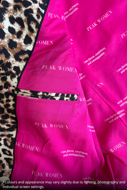 Inside pocket of a leopard-print blazer with 'PEAK WOMEN' printed in white text, laid flat on a leopard print fabric background.