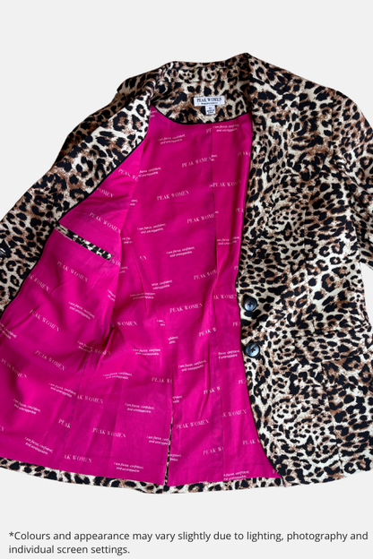 A leopard print blazer with a vibrant pink lining, laid flat on a speckled stone surface. The brand name 'PLAID WOMEN' is visible on the inner lining and neck label.