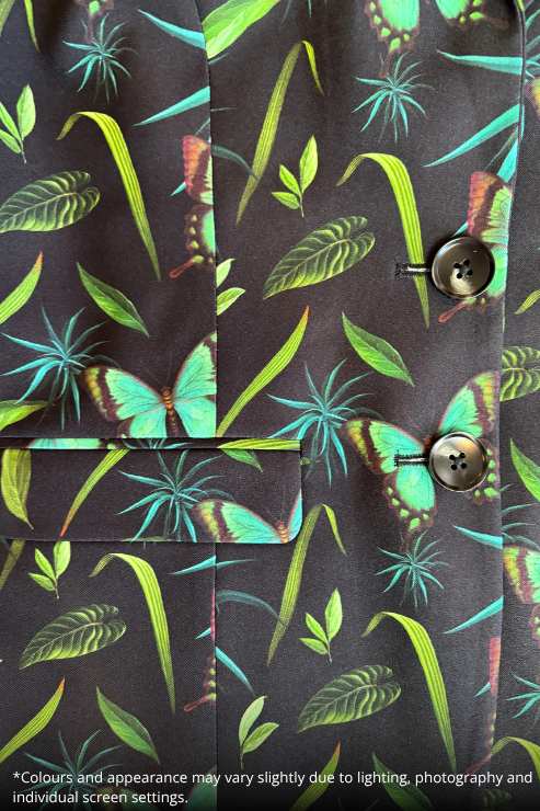 Close-up of a dark tropical print fabric with green leaves, blue-green tropical flowers, and butterflies, featuring two brown buttons on the front.