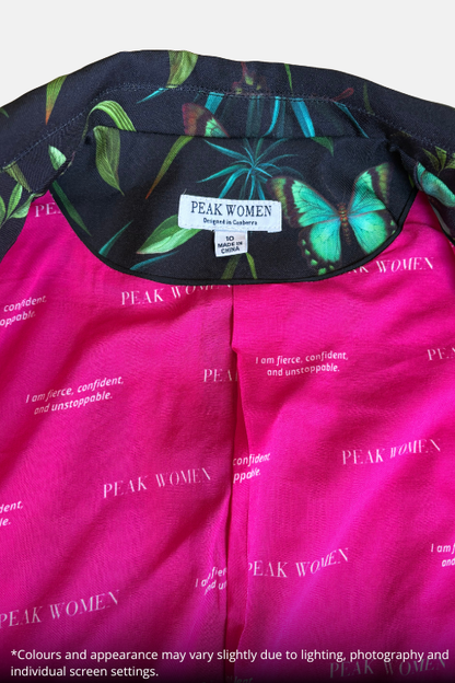 Close-up of a pink and black printed garment with butterfly and leaf patterns, showing the inner neck label 'PEAK WOMEN' and part of the printed fabric.